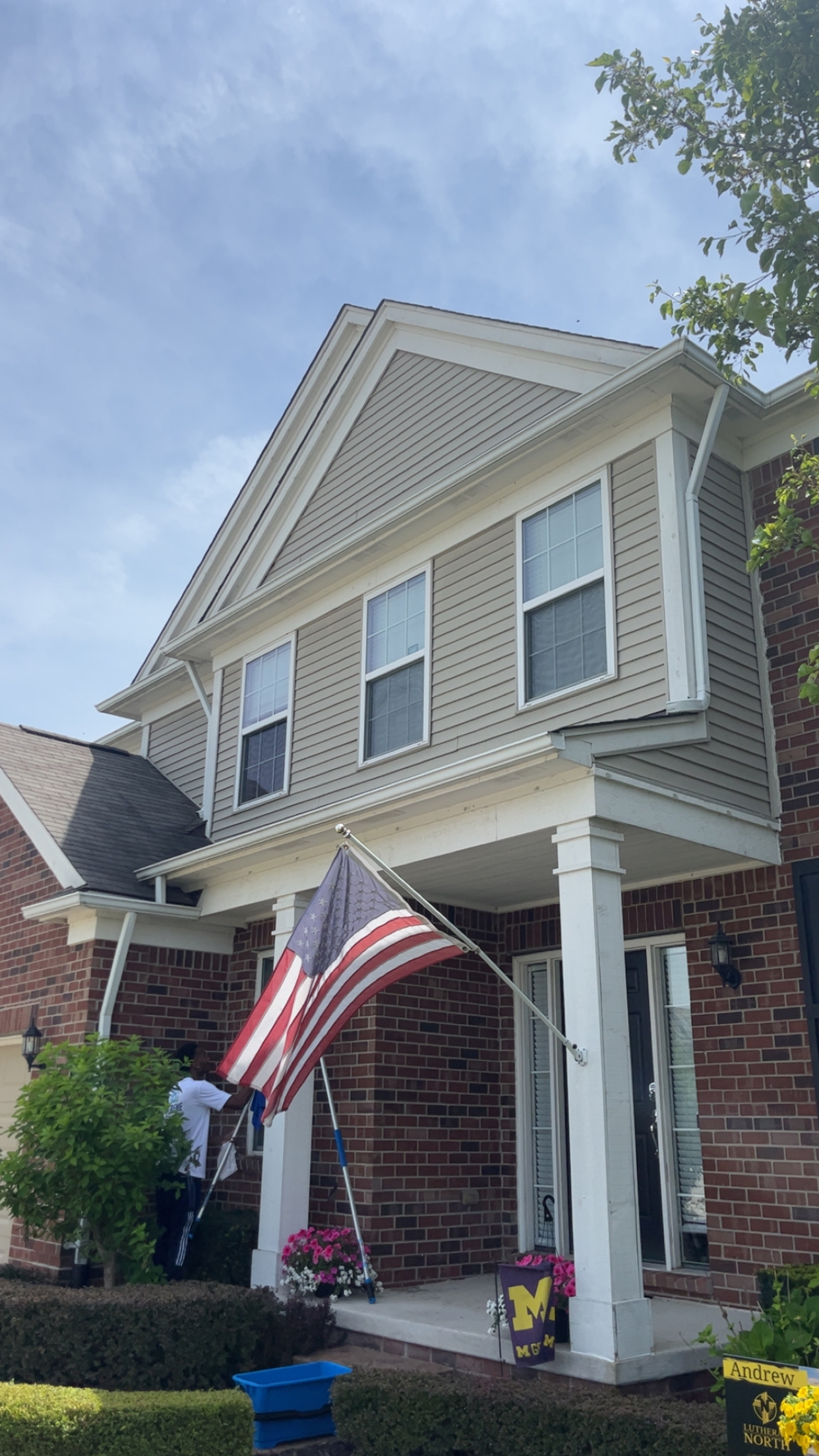 Worker cleaning windows on brick residential home