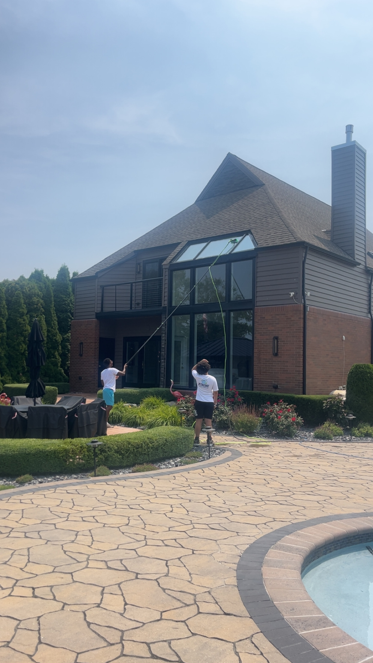 Two Xtreme workers cleaning large windows by pool