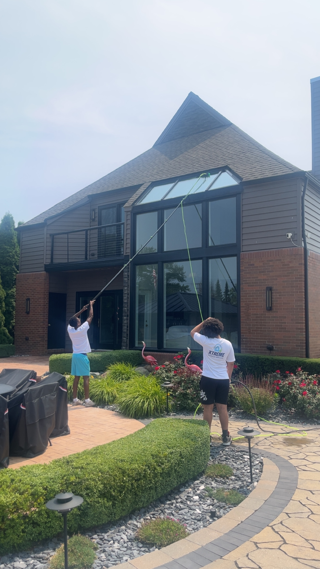 Xtreme team cleaning tall windows on luxury home